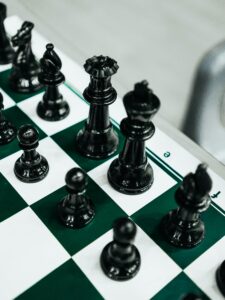 Close-up of elegant black chess pieces on a classic green and white checkered board.